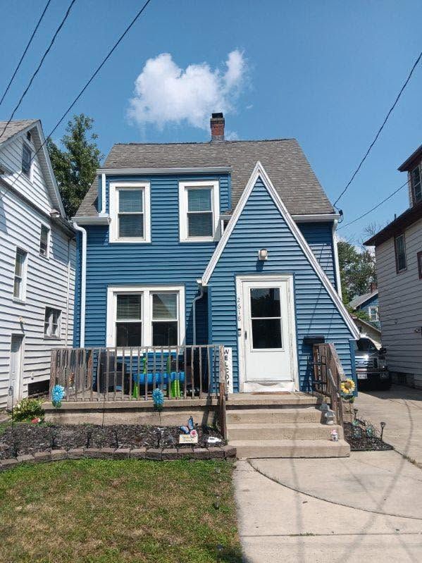 Blue two-story house with white trim, front porch, and stairs leading up from a sidewalk