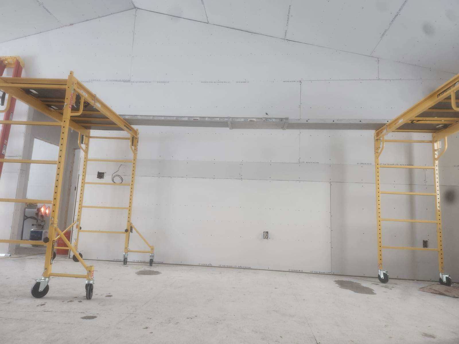 Empty room with two yellow rolling scaffolding towers against a white wall and ceiling.