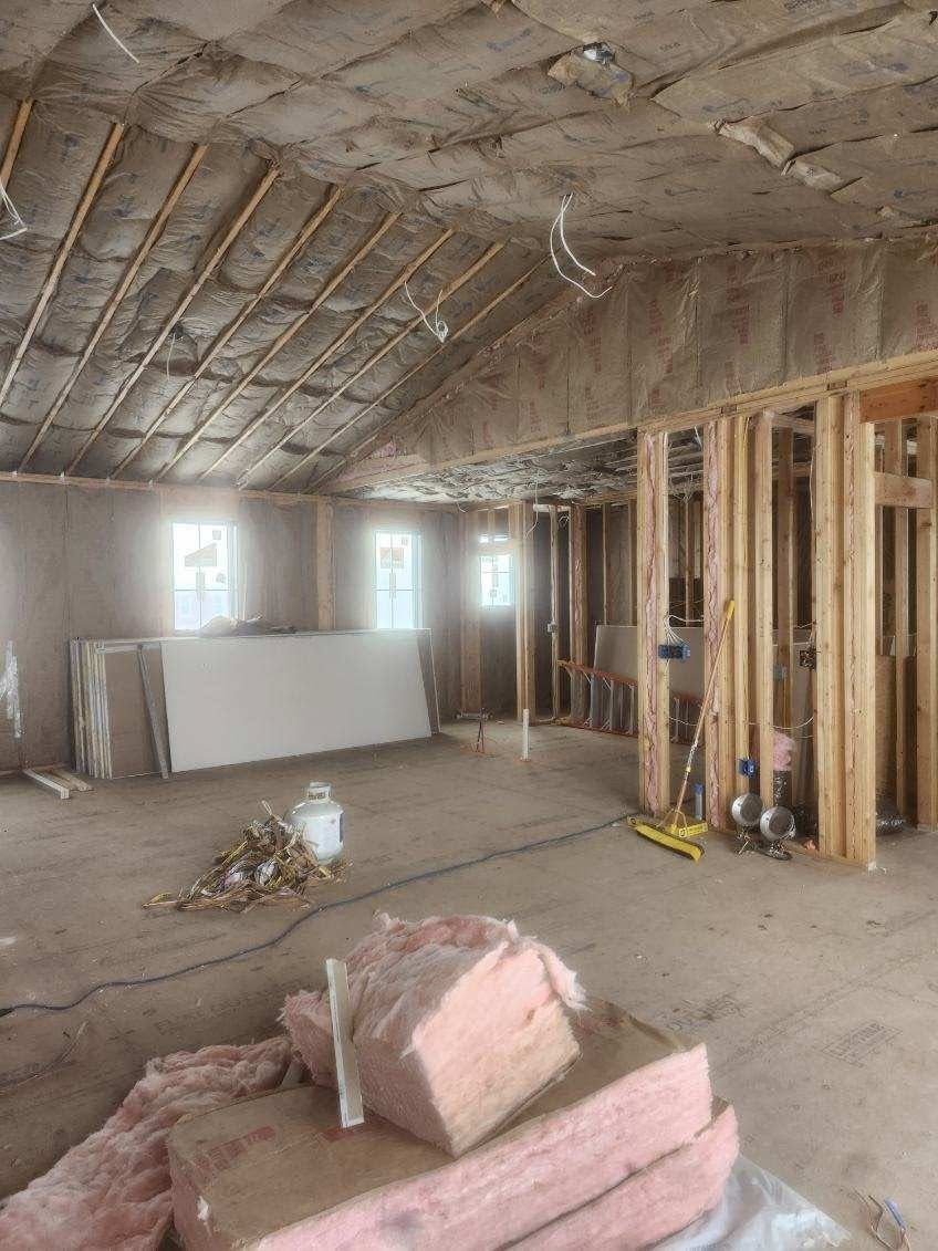 Unfinished room with exposed walls, insulation, and construction materials on the floor