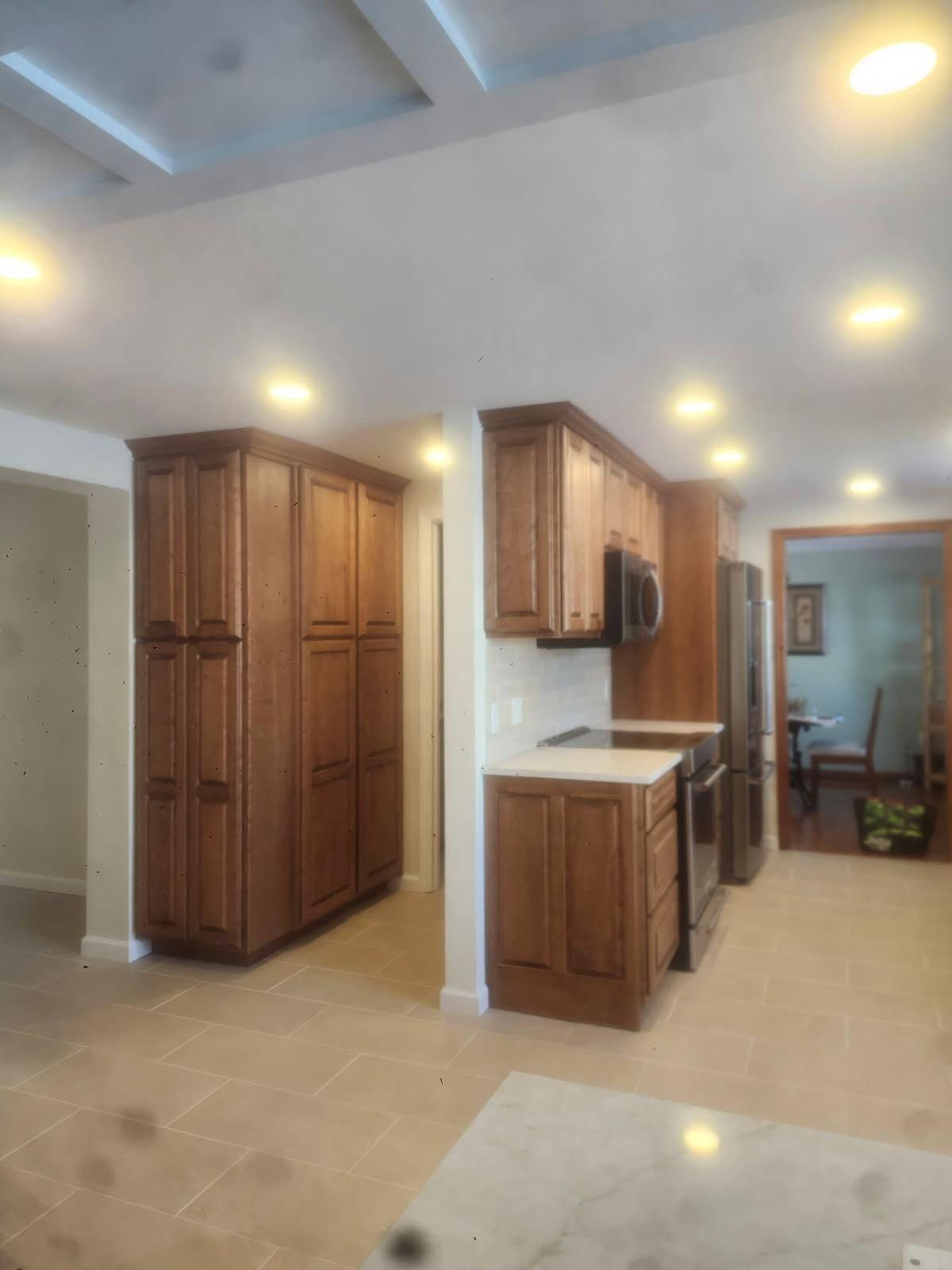 Bright kitchen with wood cabinets, beige tile floor, and recessed ceiling lights.