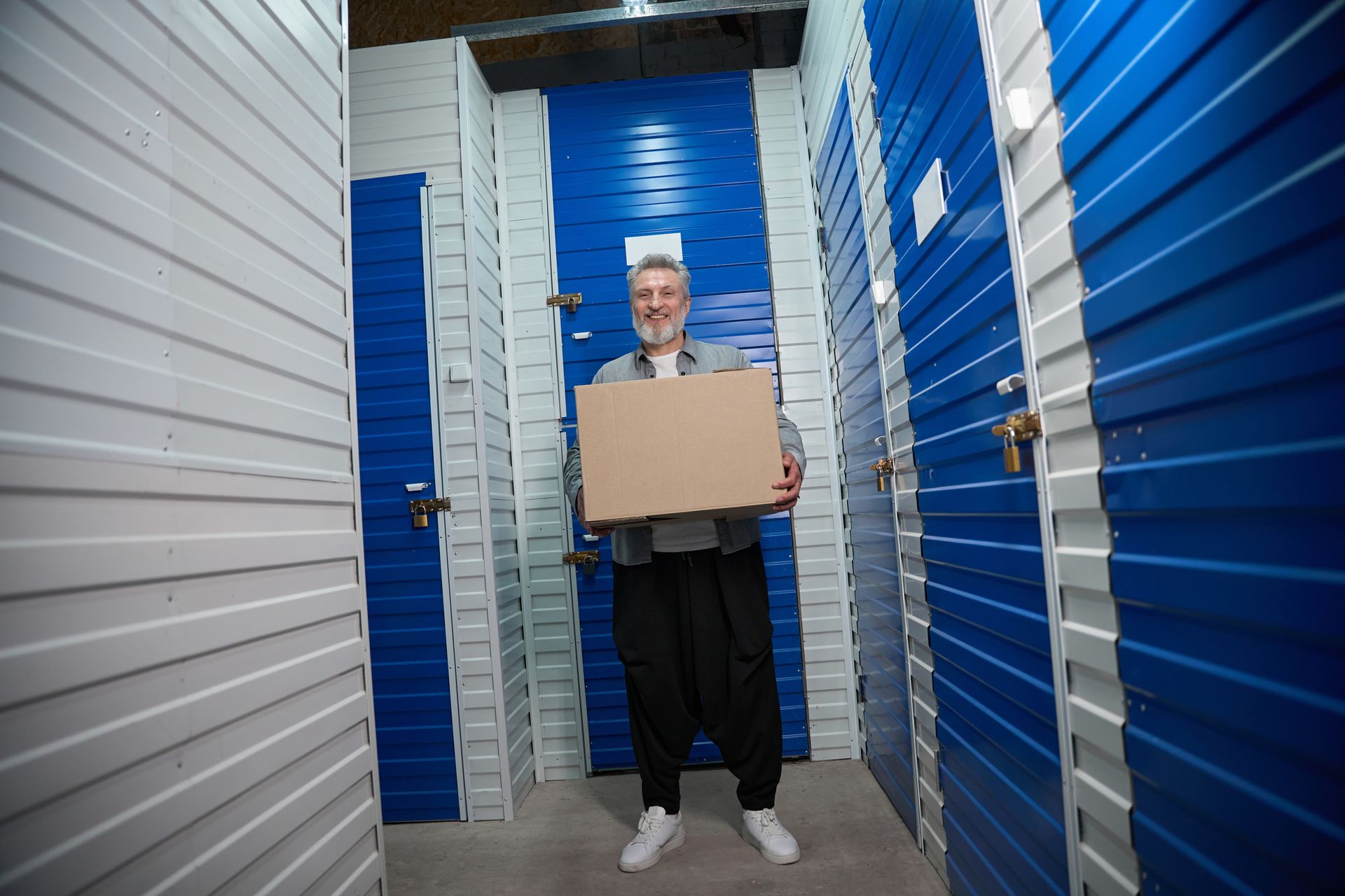 Person with cardboard boxes in a storage facility with blue unit doors. Person with cardboard boxes in a storage facility with blue unit doors.