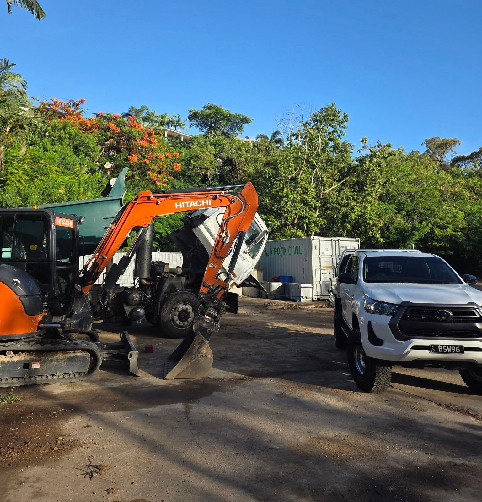Mini Excavator Next to a White Truck With Trees and Blue Sky in the Background — Waite Diesel Service in Douglas, QLD