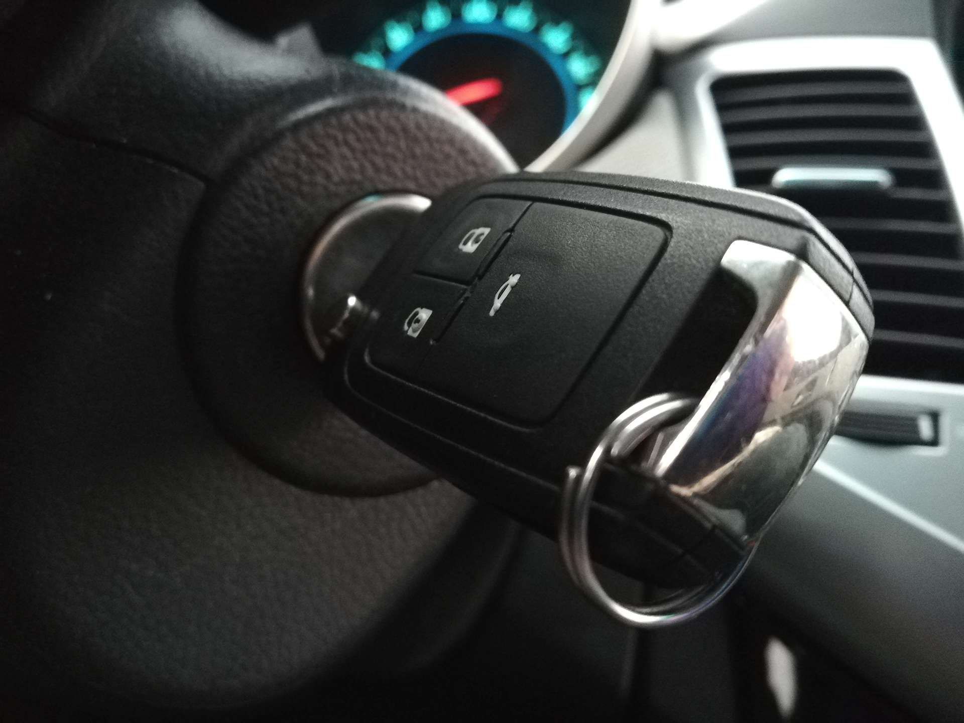 Close-up of a car key in the ignition with dashboard and steering wheel visible