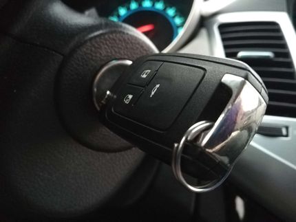 Close-up of a car key in the ignition with dashboard and steering wheel visible