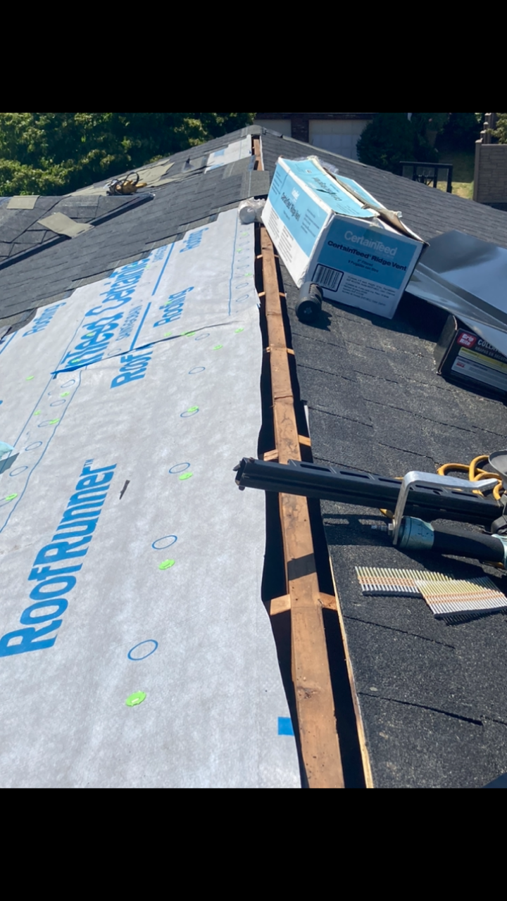 Roofing work in progress; felt paper and shingles visible on a black asphalt roof.