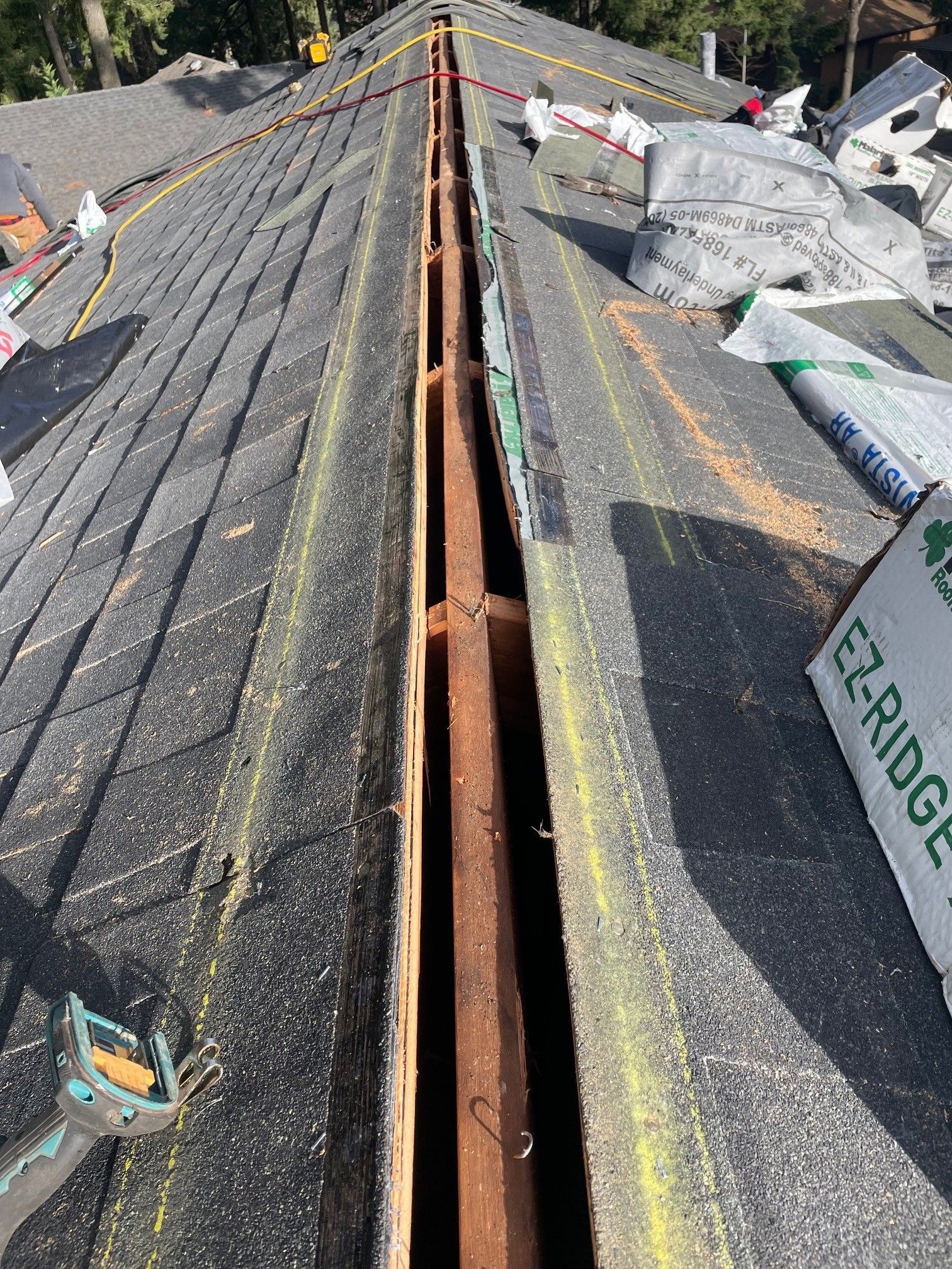 Rooftop valley under construction; old shingles removed. Exposed wood framing. New roofing materials are visible.