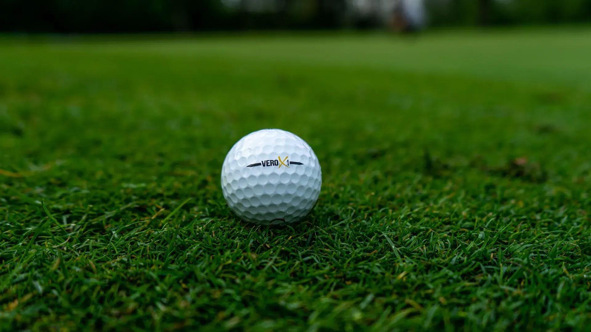 A white golf ball on green grass with a blurred fairway background