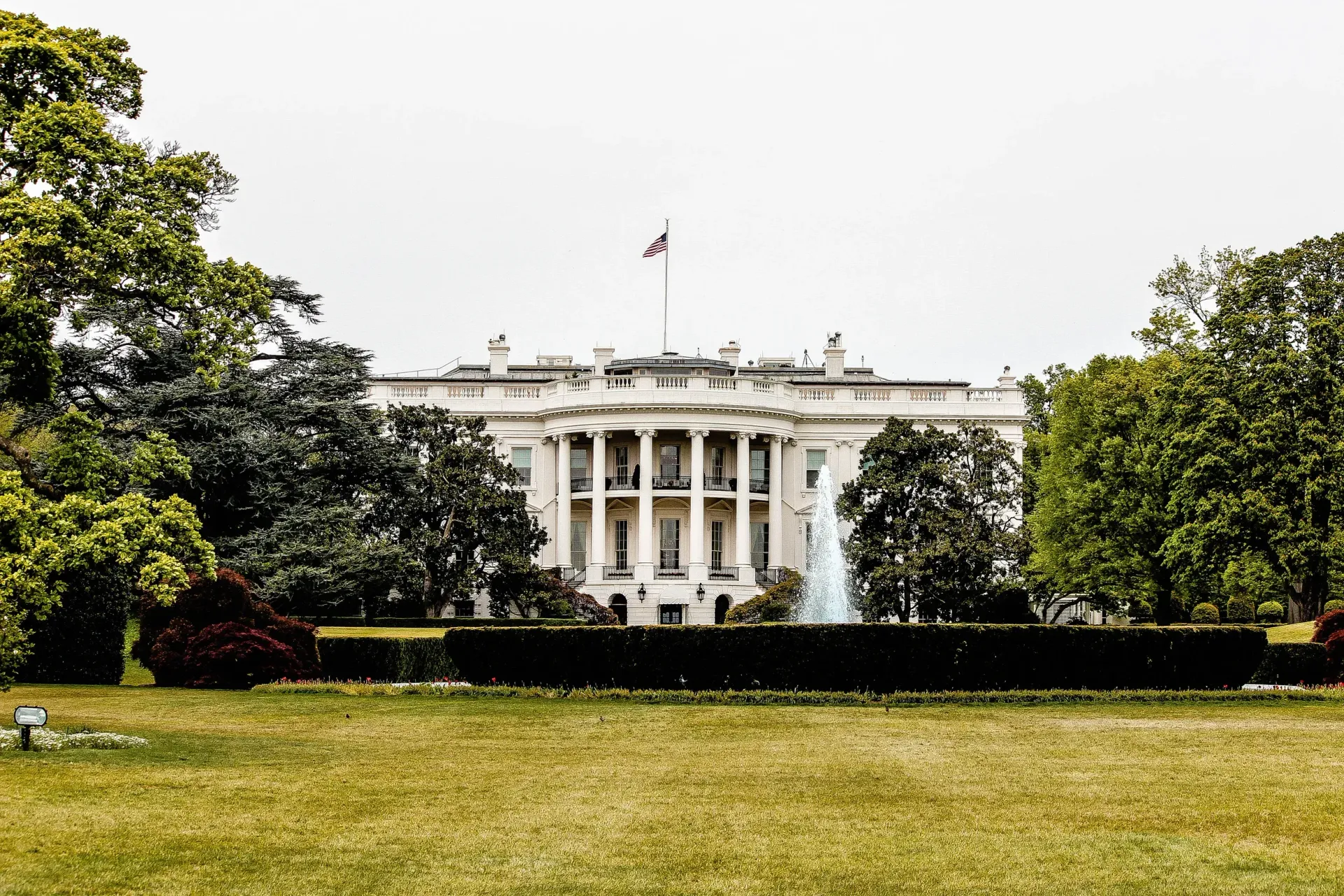 The White House behind trees and lawn under a bright sky