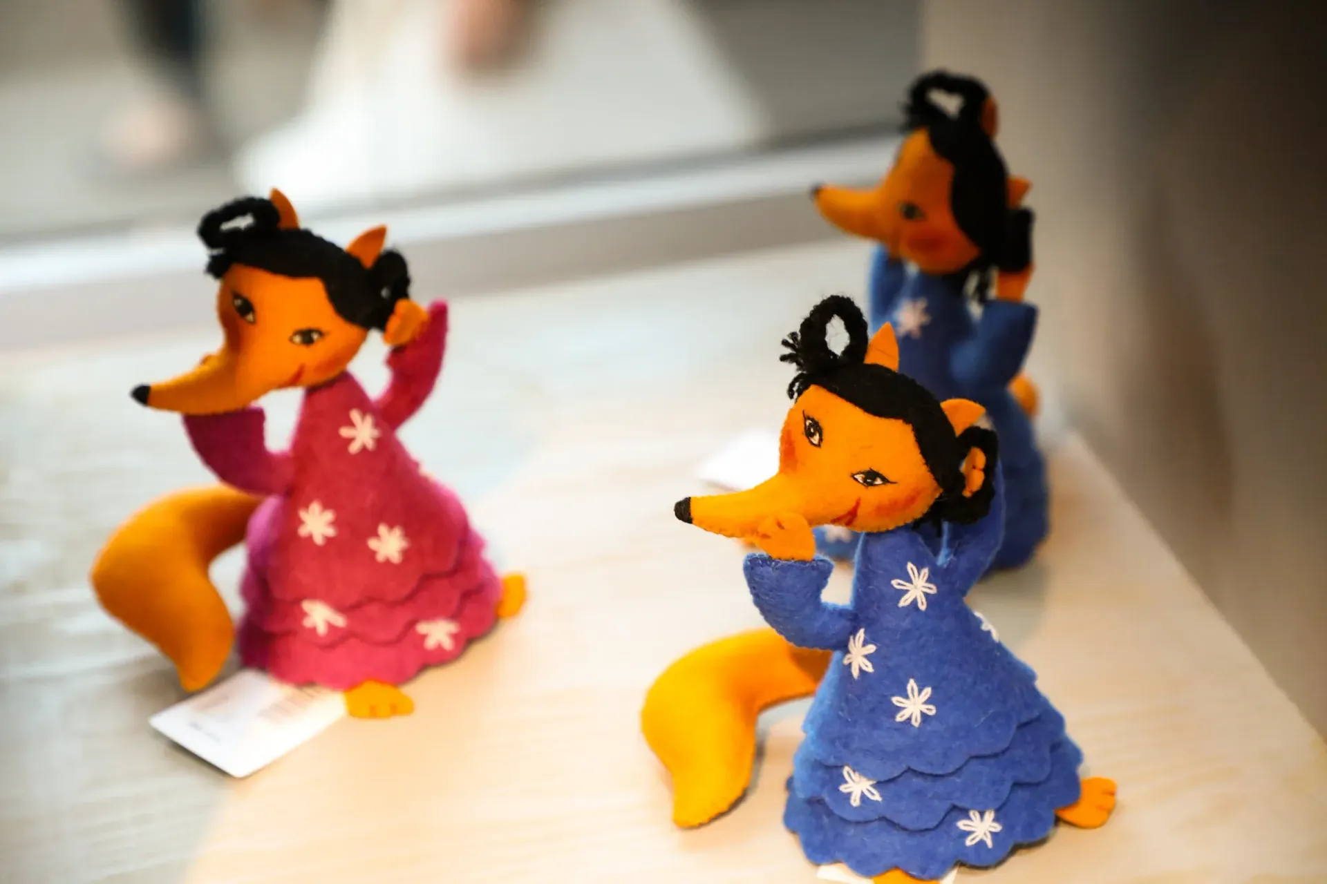 Three small fox figurines in colorful star-patterned sweaters on a table
