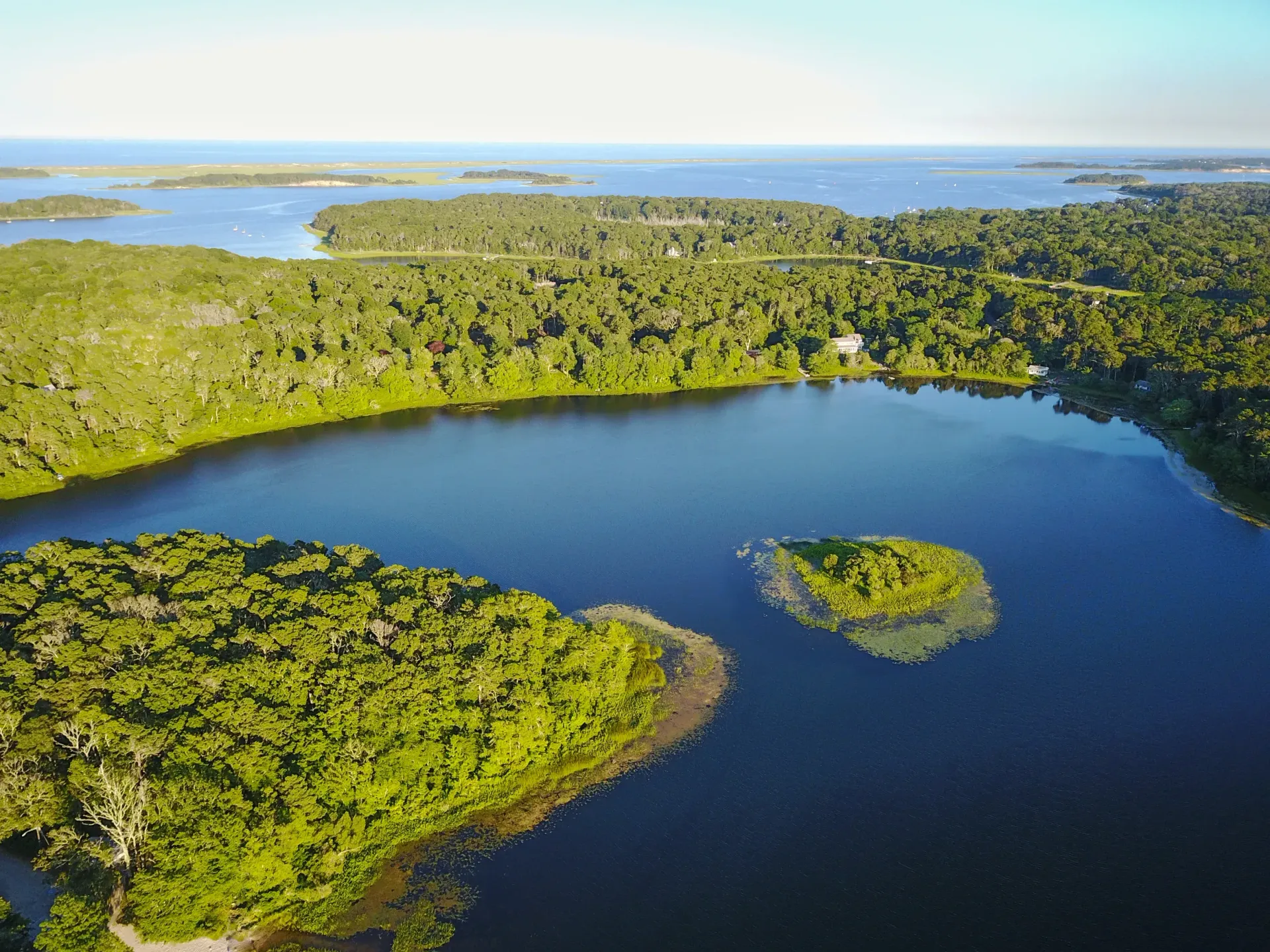 Aerial view of a blue lagoon surrounded by dense green forest and small islands near the coast