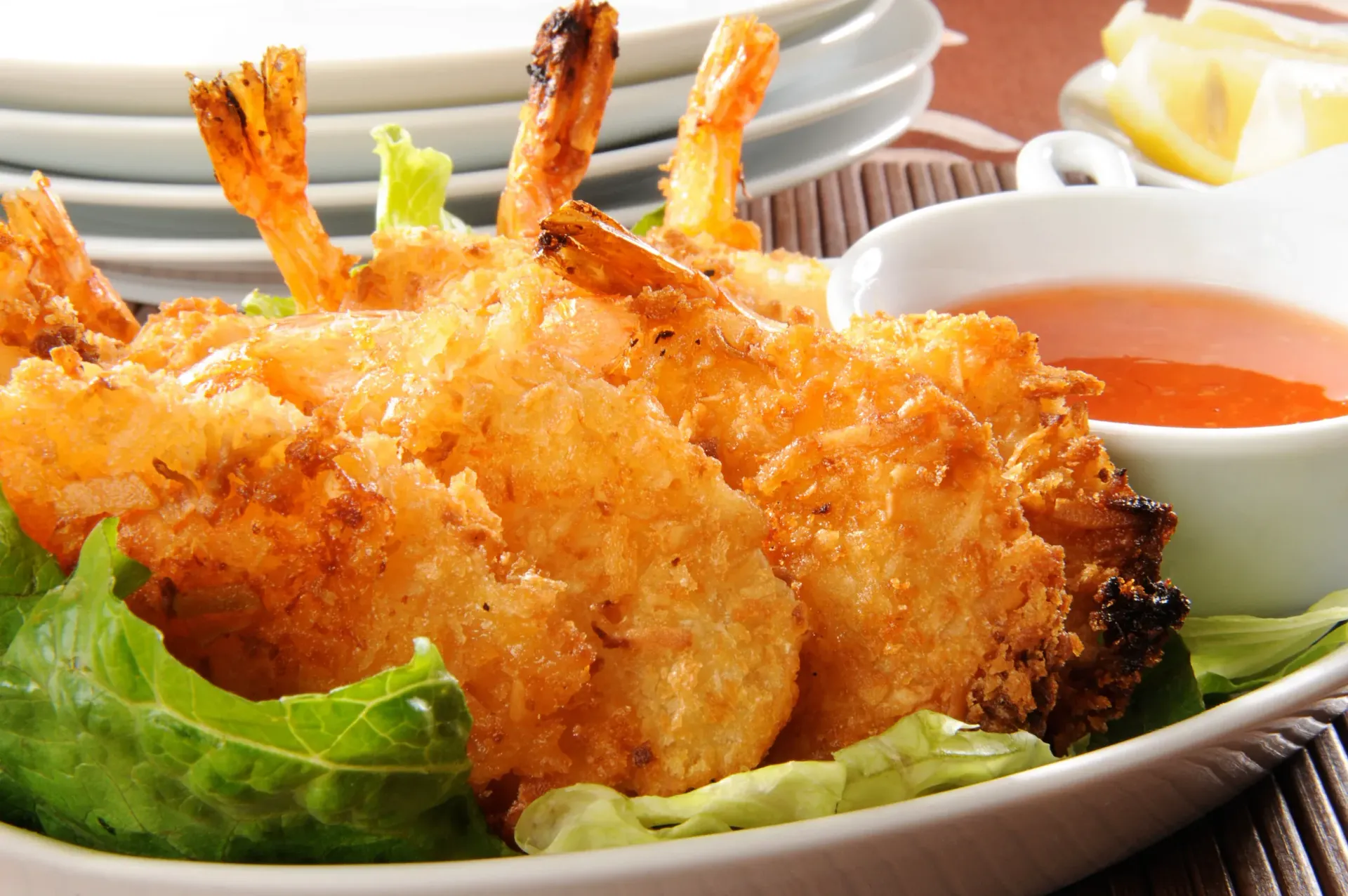 Golden-brown fried shrimp on lettuce with a side of orange dipping sauce