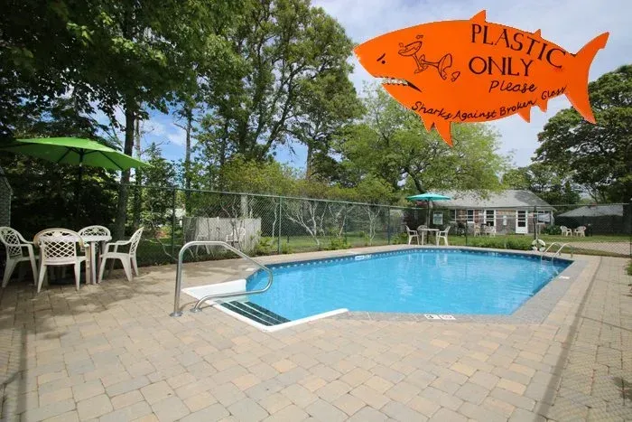 Outdoor pool with blue water, patio chairs, trees, and an orange 