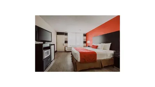 A hotel room with a king size bed and a flat screen tv.