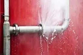 A pipe is leaking water on a red wall.