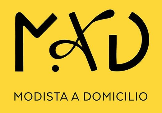 Logotipo negro sobre fondo amarillo con la inscripción “MODISTA A DOMICILIO” y las letras “MAD” estilizadas.