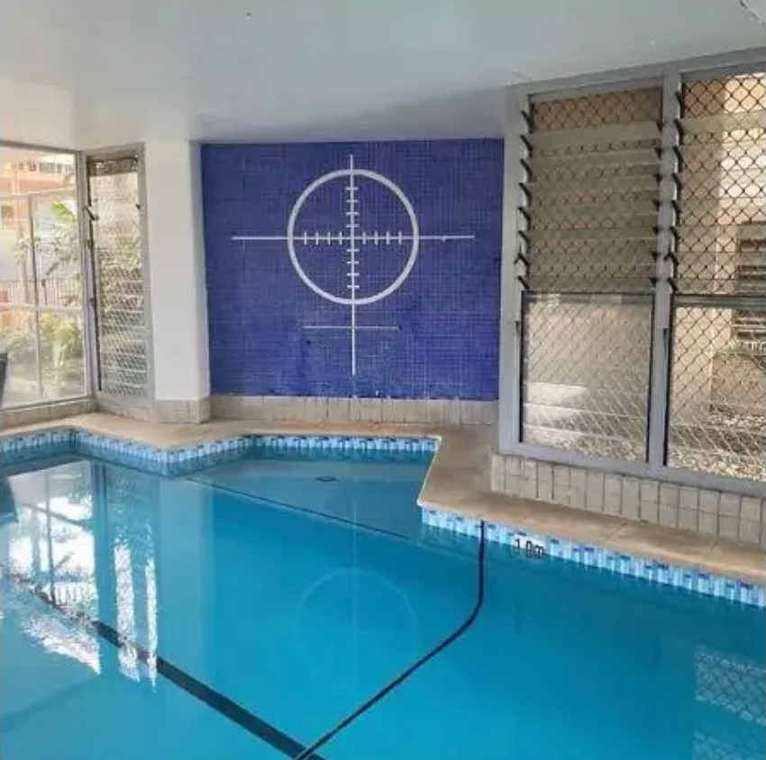 Indoor swimming pool with blue tiles, featuring a white crosshair symbol on the back wall. — East Coast Pool Resurfacing In Port Macquarie, NSW
