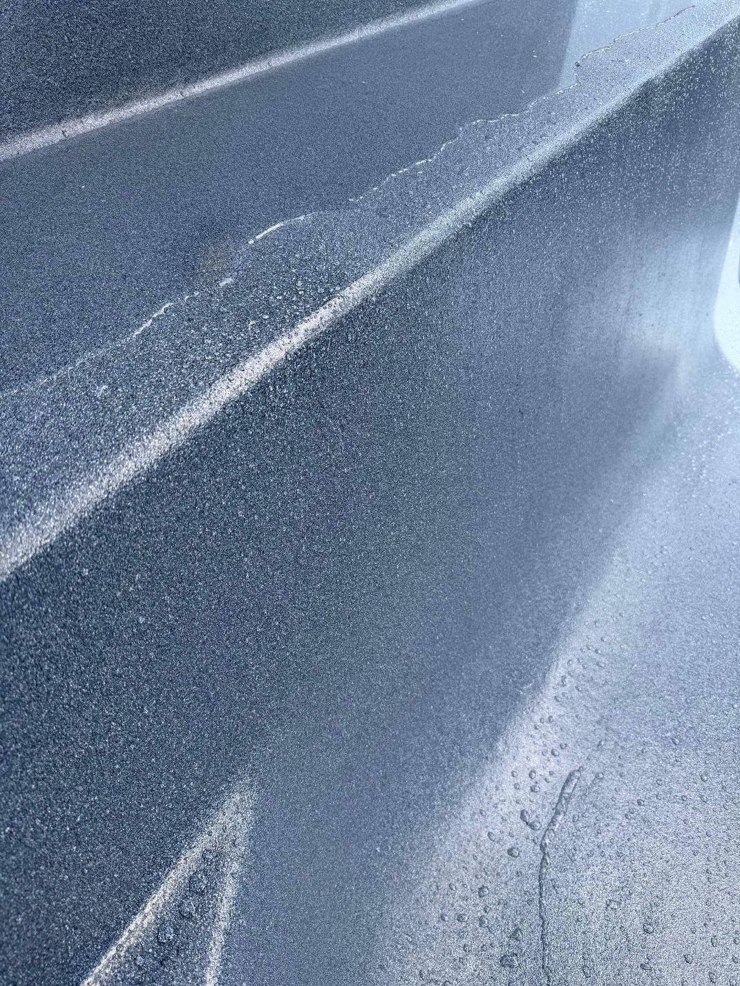 A dark blue surface with water droplets and a bright light reflection — East Coast Pool Resurfacing In Port Macquarie, NSW