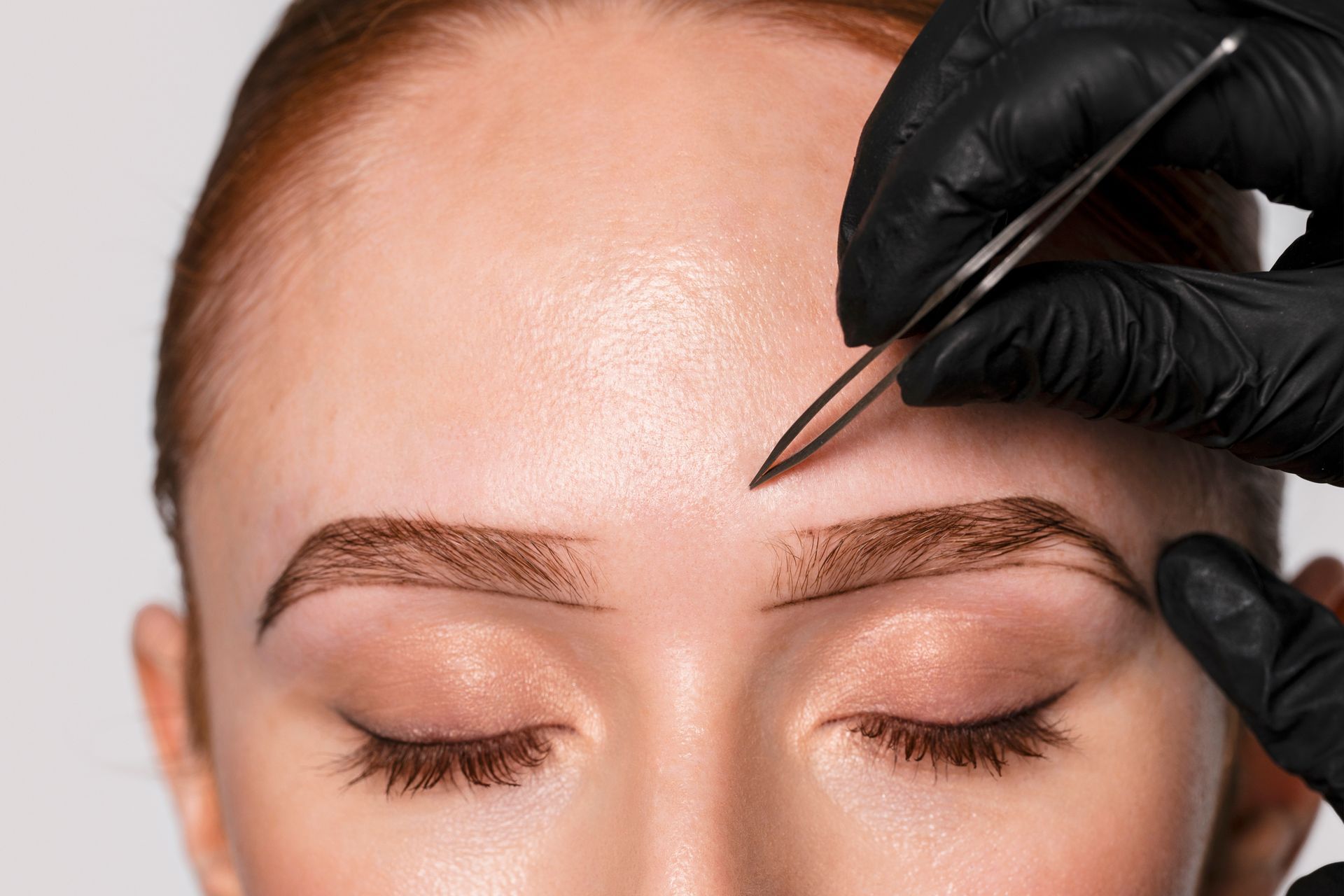 Person getting eyebrow waxed; blue wax applied with a wooden stick.