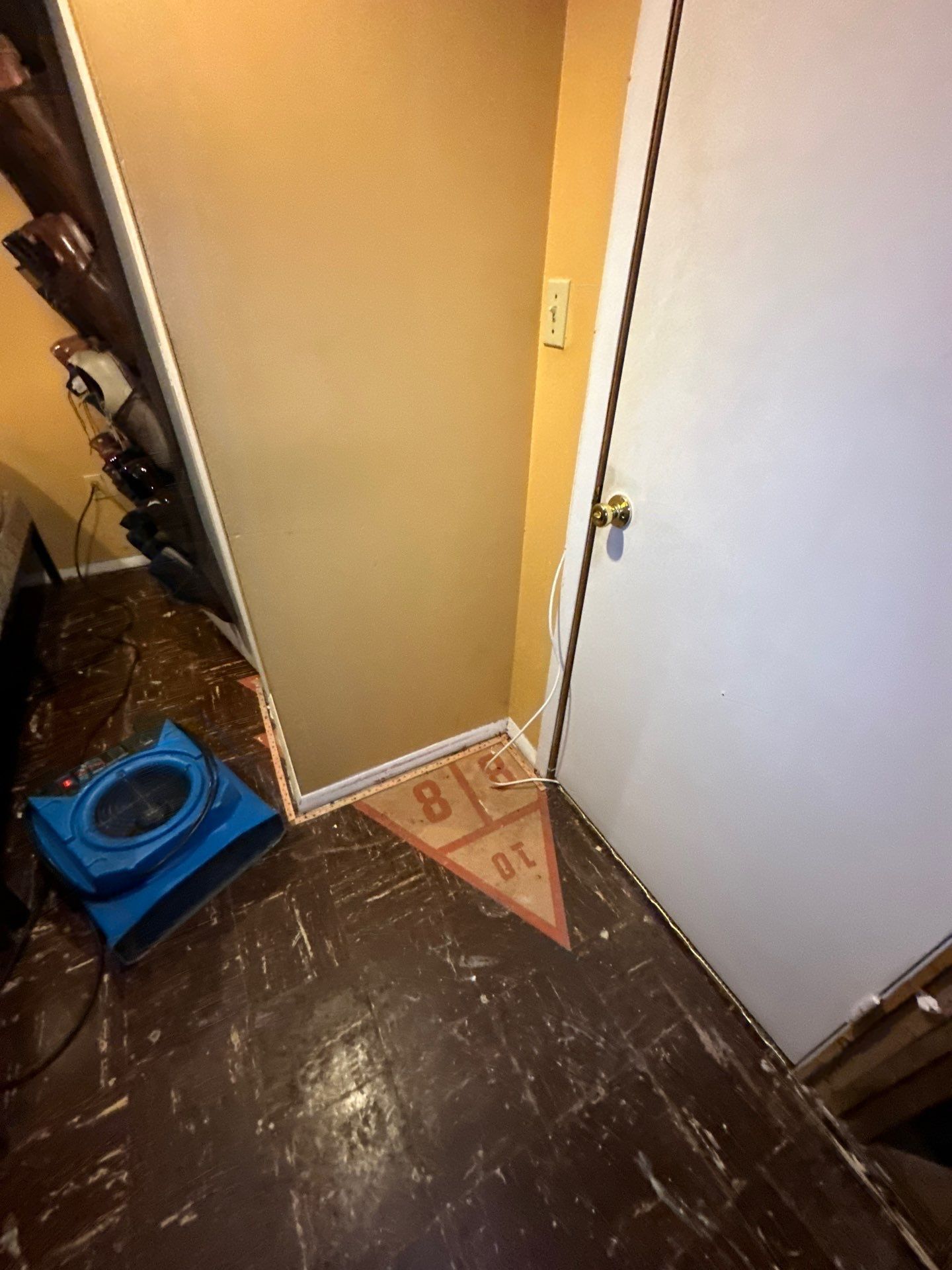 Person in white protective suit and respirator inspects a moldy basement wall with a flashlight.