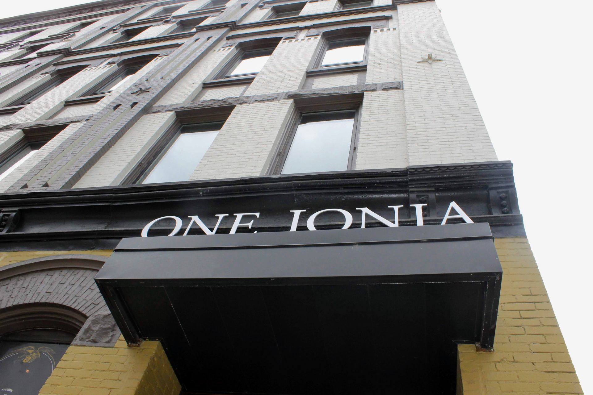 Building entrance with black awning reading “ONE IONIA” against a tall stone facade