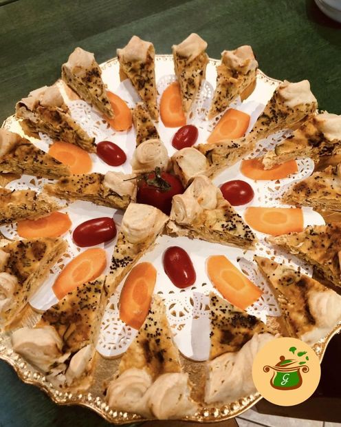 Piatto di antipasti con pasticcini triangolari, fette di carota e pomodori.
