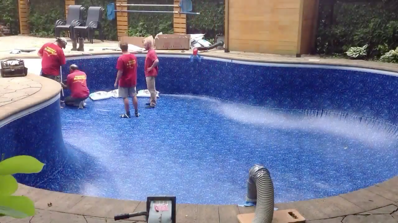 Des enfants jouent dans une piscine bleue vide, de l'eau jaillissant de jets d'eau.
