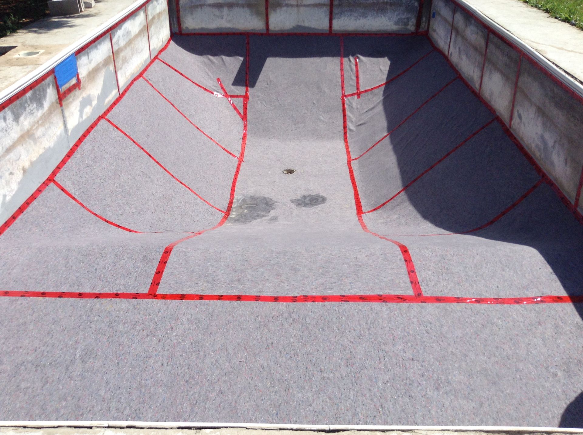 Rampe ou quai de chargement en béton à revêtement rouge, avec des parois grises et une tache centrale foncée.