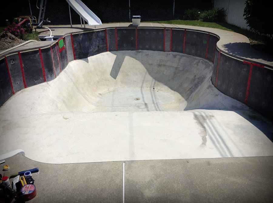 Skatepark en béton vide avec rambardes rouges la nuit