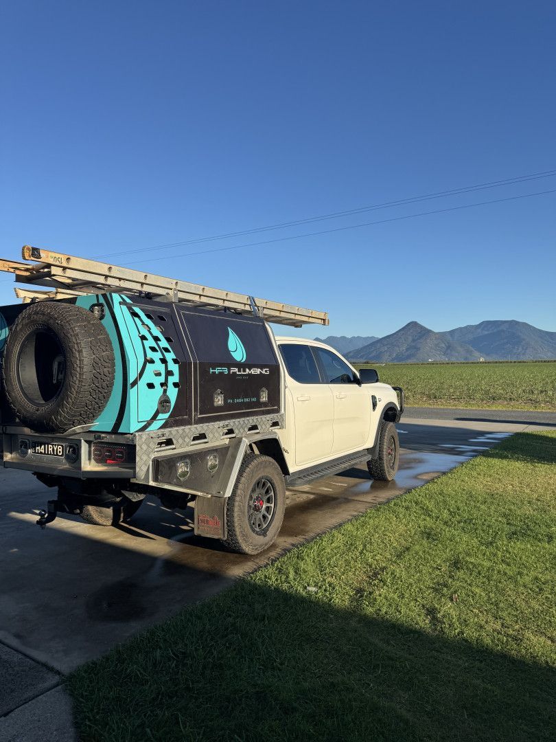 White Pickup Truck With Water Tank and Ladder on a Paved Area With Mountains and a Blue Sky in the Background — HFB Plumbing & Gas in Wrights Creek, QLD