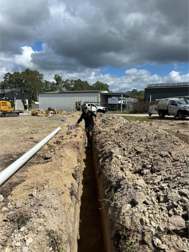 A Worker Stands in a Trench Beside a White Pipe — HFB Plumbing & Gas in Edmonton, QLD