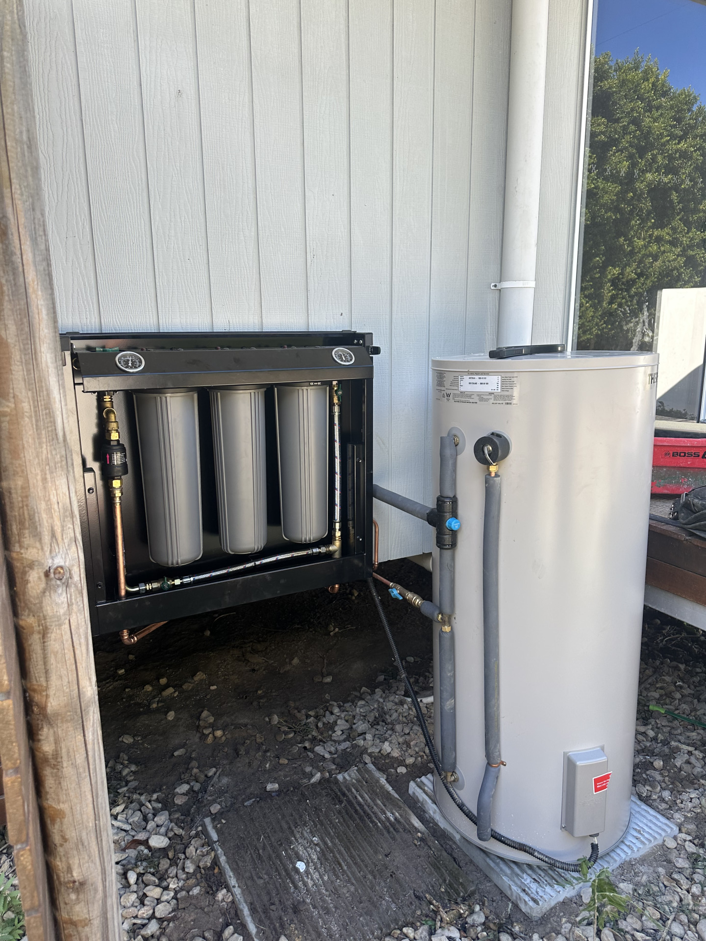 Water Filtration System and Water Heater Mounted on the Exterior of a White Building - HFB Plumbing & Gas in Wrights Creek, QLD