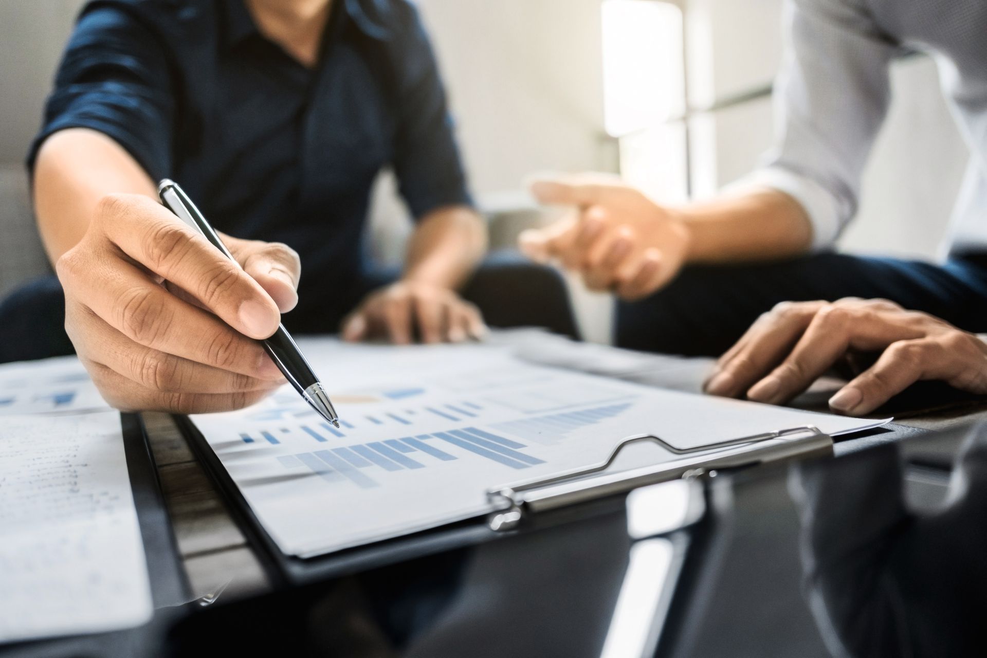 Two people reviewing charts, one pointing with a pen.