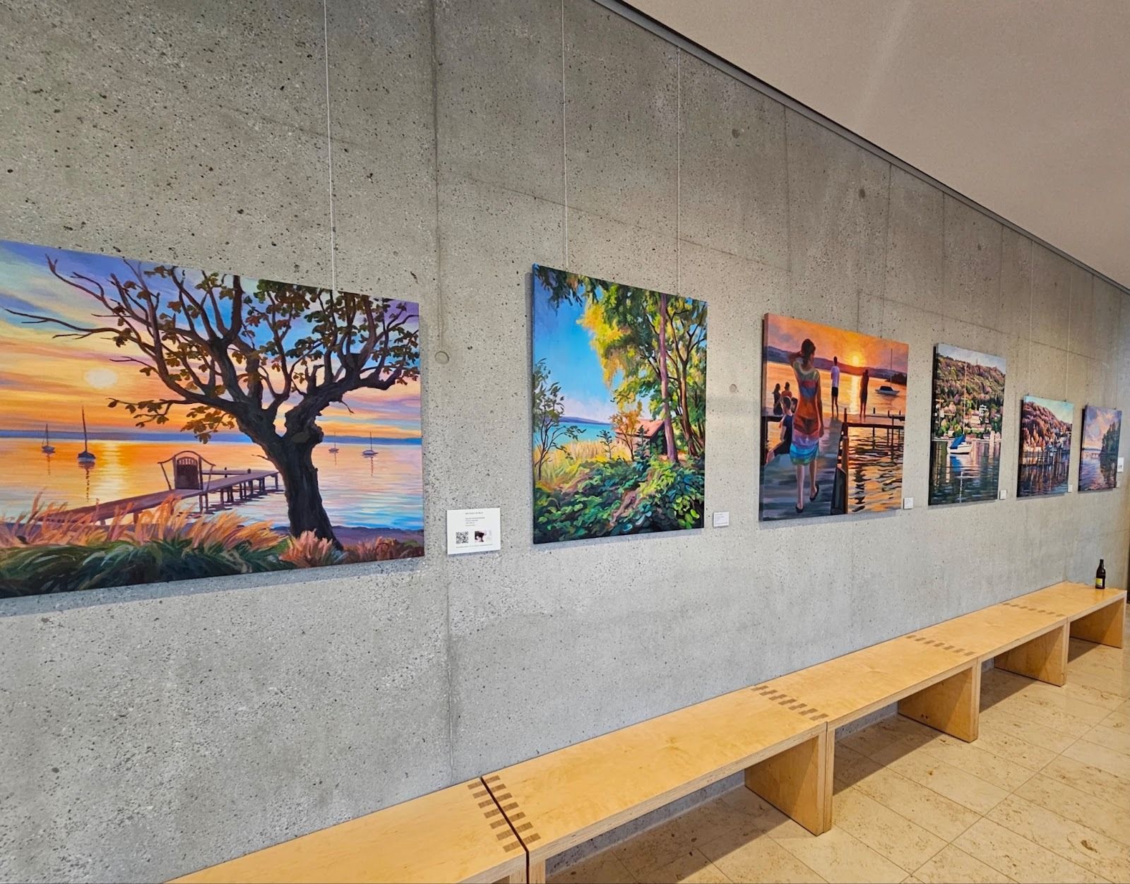 Eine Kunstgalerieausstellung mit mehreren Landschaftsgemälden.