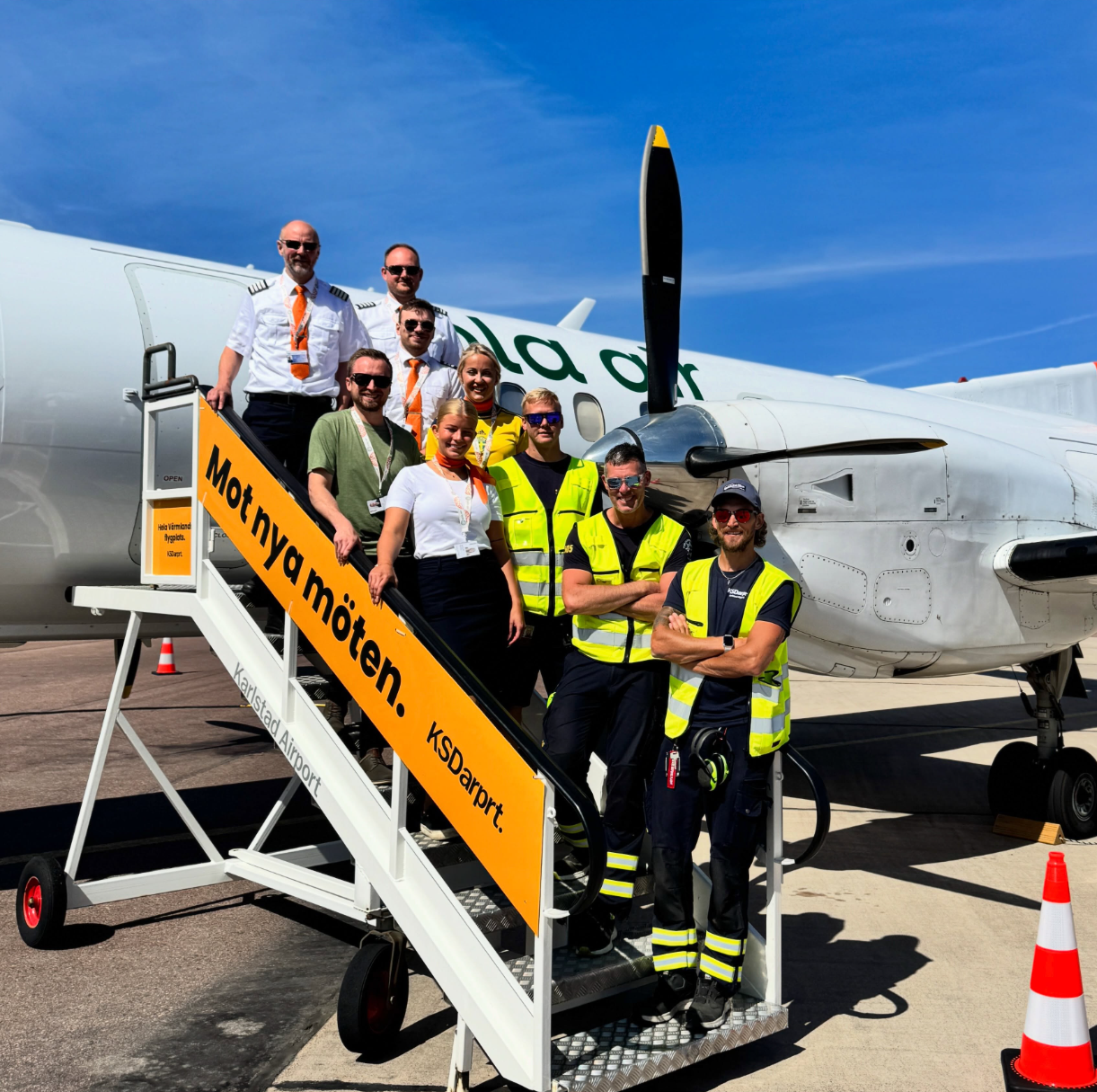 Flygplanets kabingång med en stående flygvärdinna och passagerare sittande under en UTGÅNGSskylt