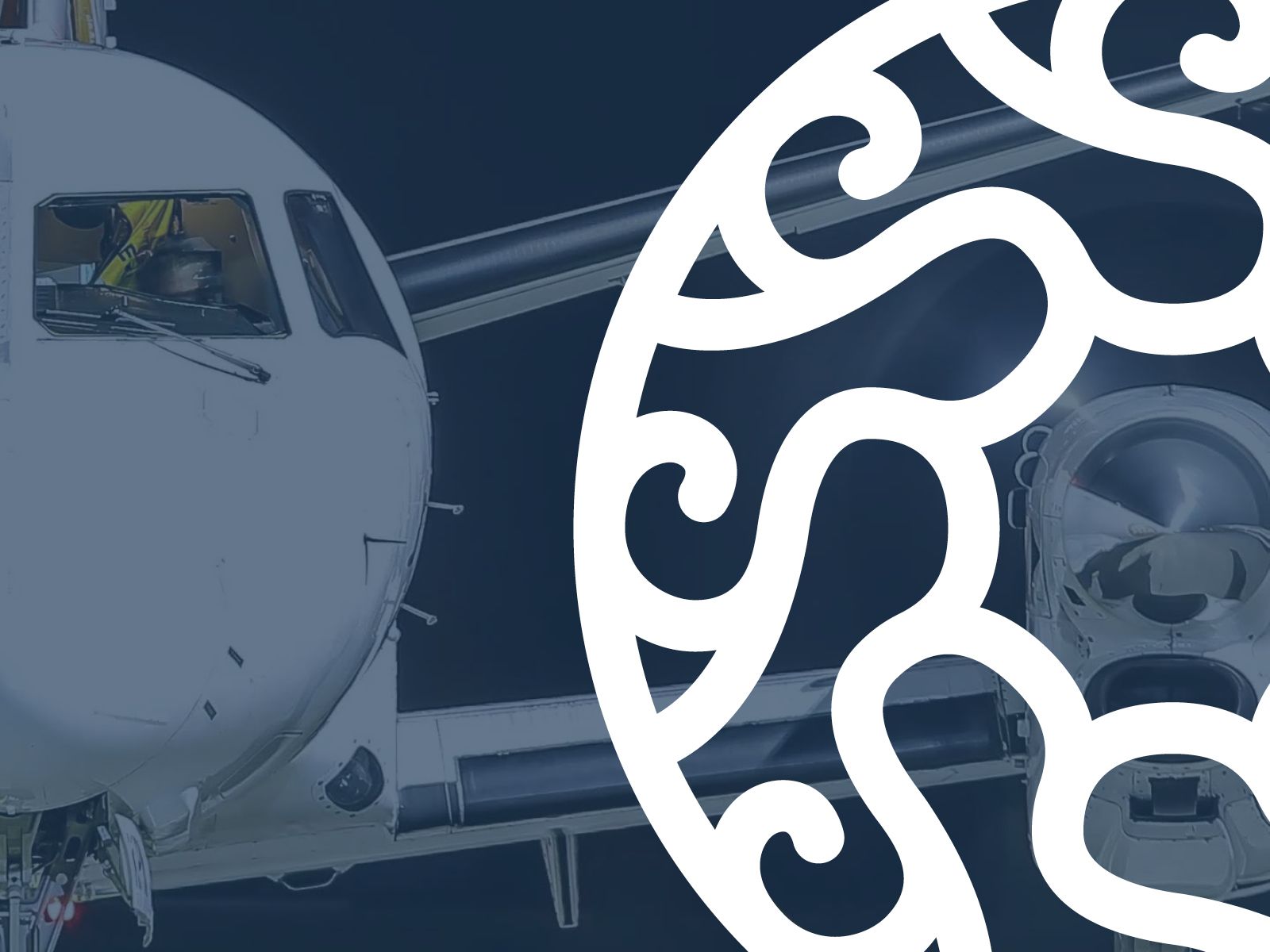 Flygplansnos och motor på en mörk asfalt, delvis täckt av ett vitt dekorativt virvelöverlägg