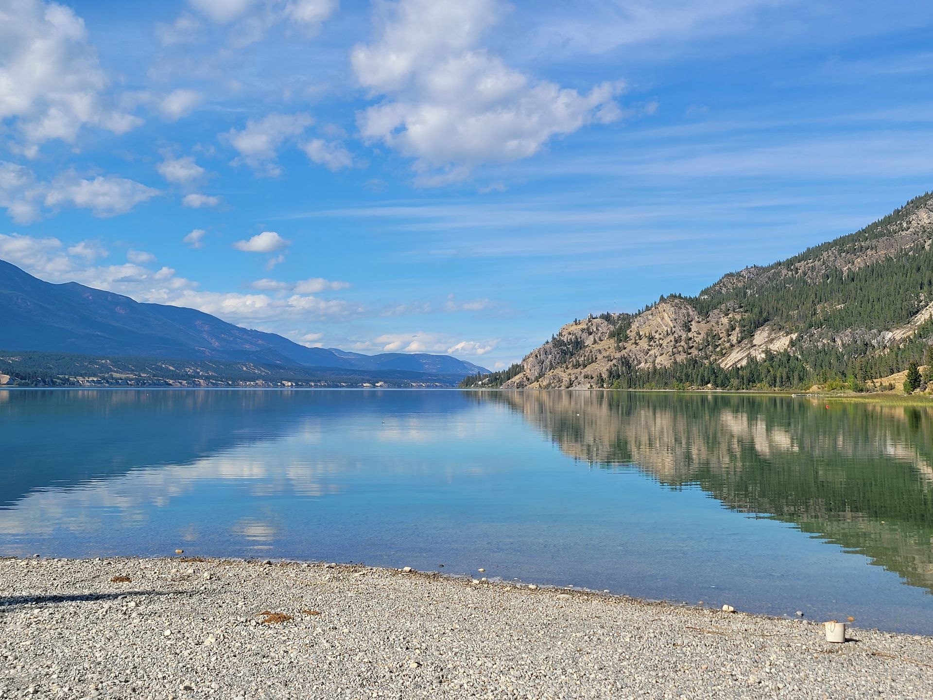 A lake with mountains in the background and a beach in the foreground.