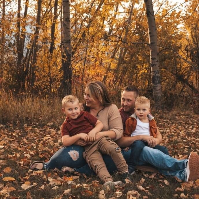 A family is sitting on a pile of leaves in the woods