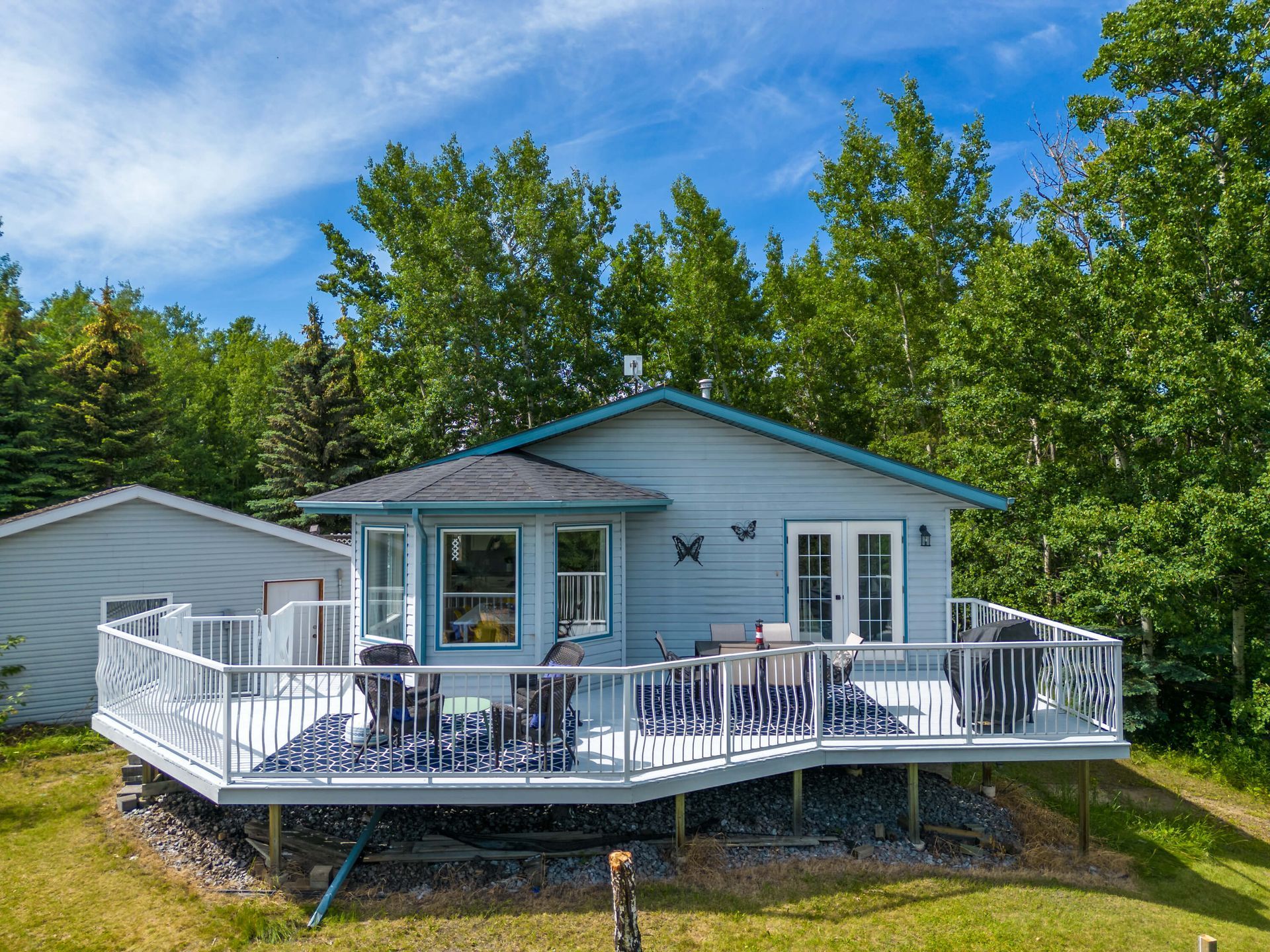 Exterior shot of a home, deck and green space located lakeside of Gull Lake, Alberta.