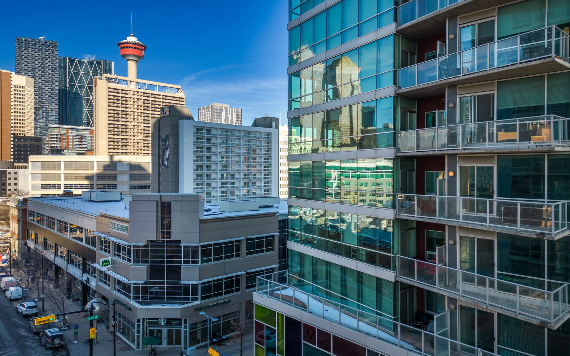 Cityscape with high-rise buildings, including the Calgary Tower, on a sunny day.