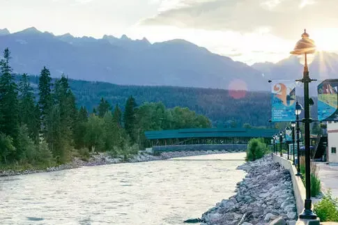 River flows under a bridge with mountains in the background, a streetlight in the foreground.
