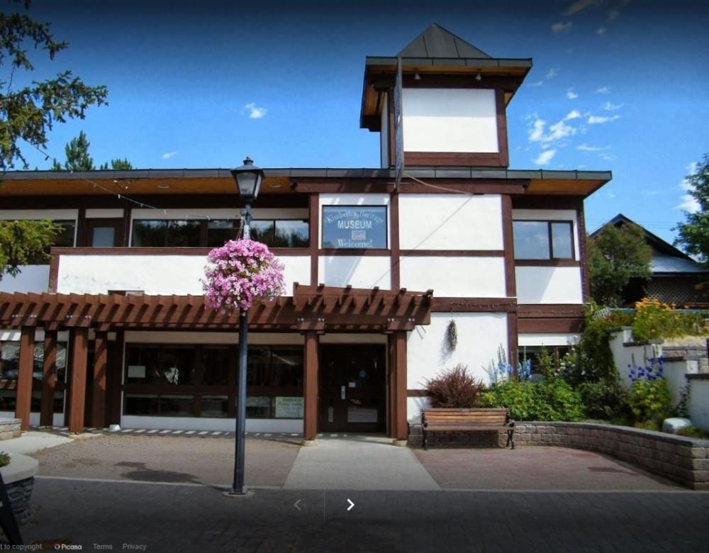 Building with white and brown exterior, small tower, hanging flower basket, sign: 