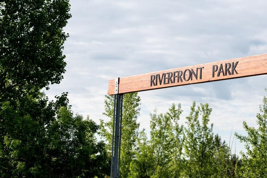 Riverfront Park sign above trees under a cloudy sky