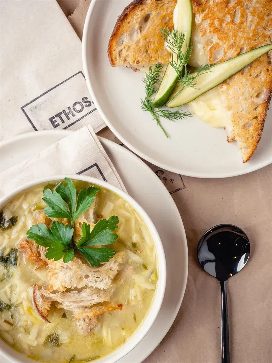 Soup bowl with bread, side of toasted bread with zucchini on a white plate; 