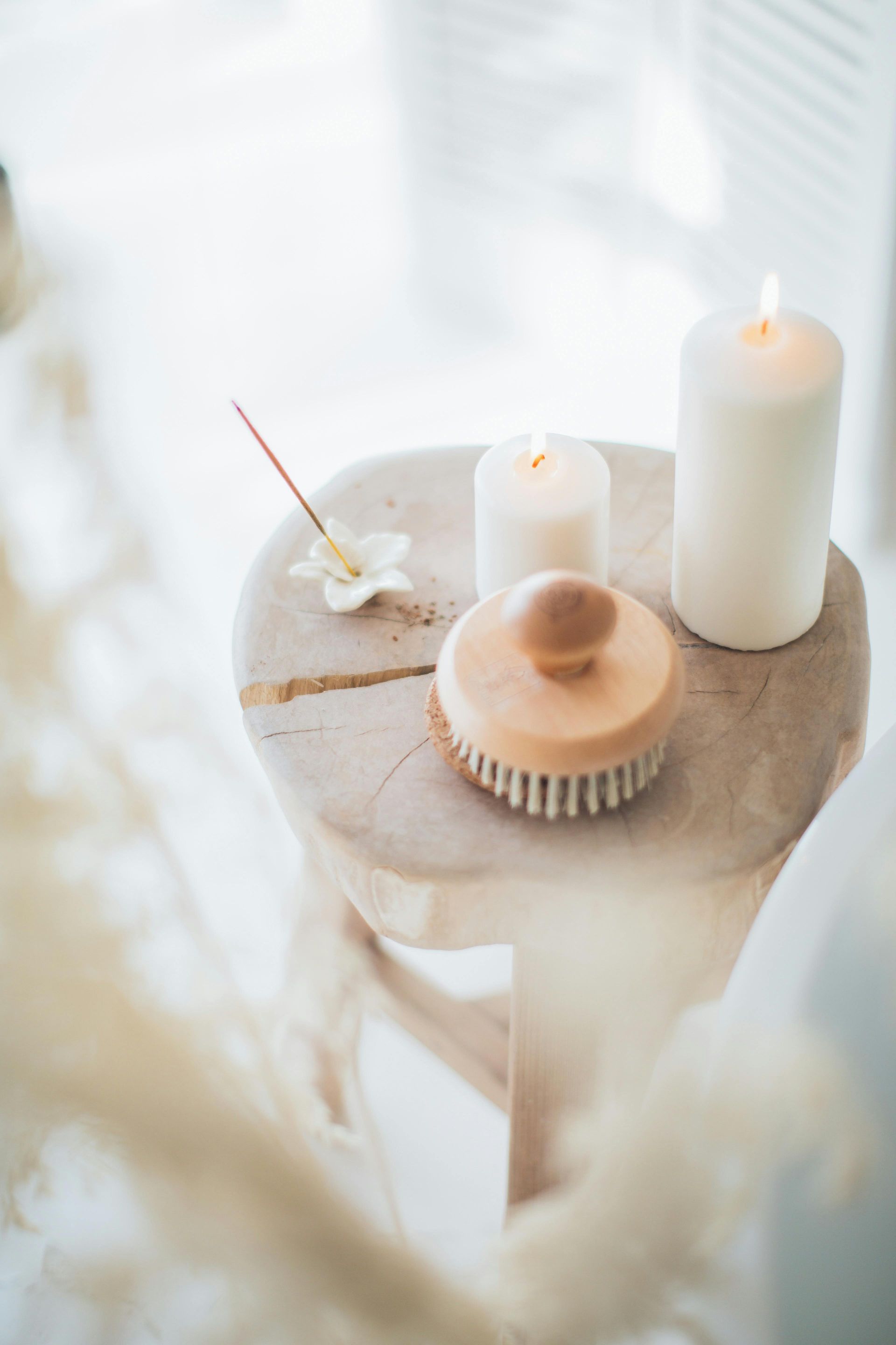 Wooden stool with candles, a brush, and incense stick, creating a spa-like ambiance.