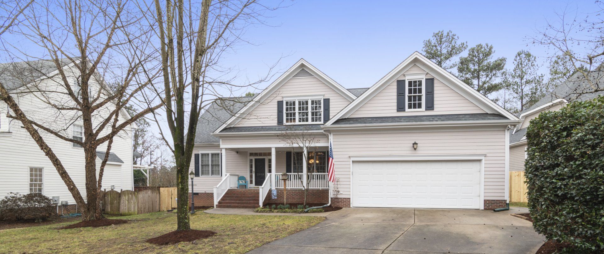 A white house with a white garage door and a porch.