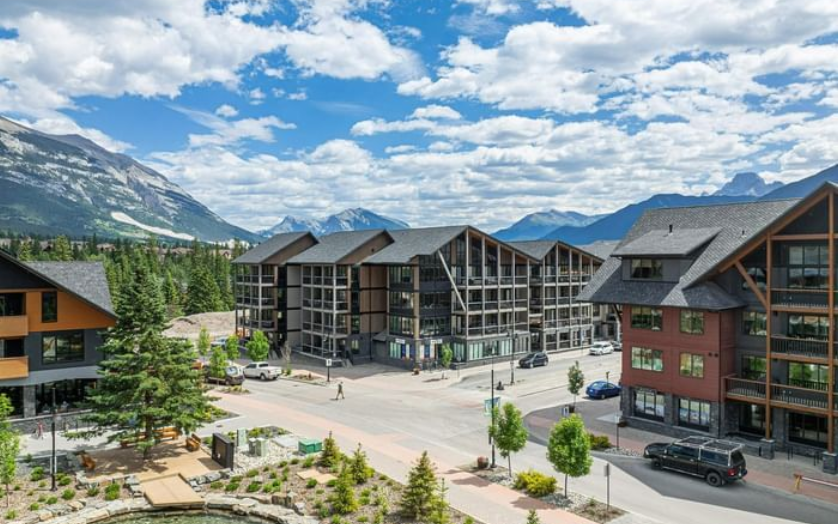 Buildings and street in mountain town under blue sky with clouds.