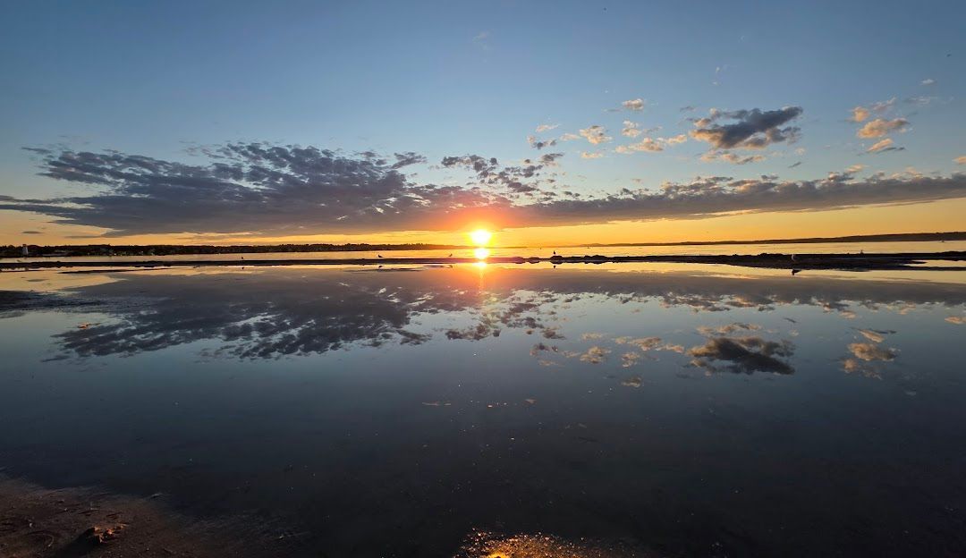 Sunset over calm water reflecting the colorful sky and clouds.