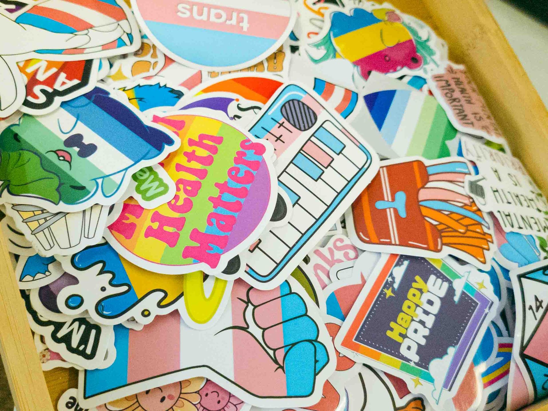 Colorful sticker pile with “Harry Styles” and “Harry Potter” designs on a wooden surface