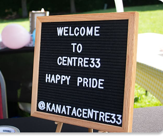 Black sign with white letters says “Welcome to Centre33 Happy Pride @KanataCentre33.”