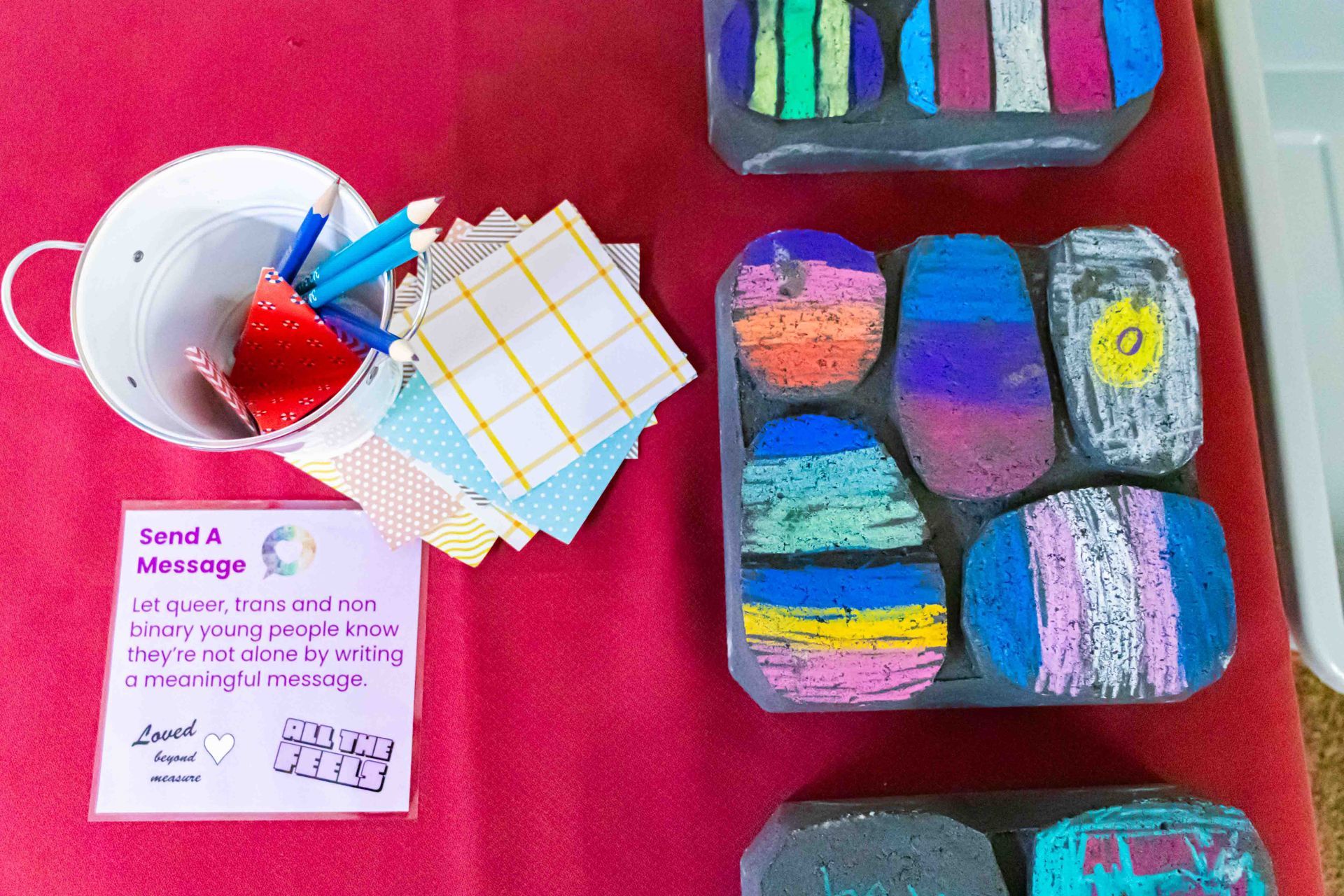 Art supplies on a red table: cup of paintbrushes, colorful swatches, and painted block samples